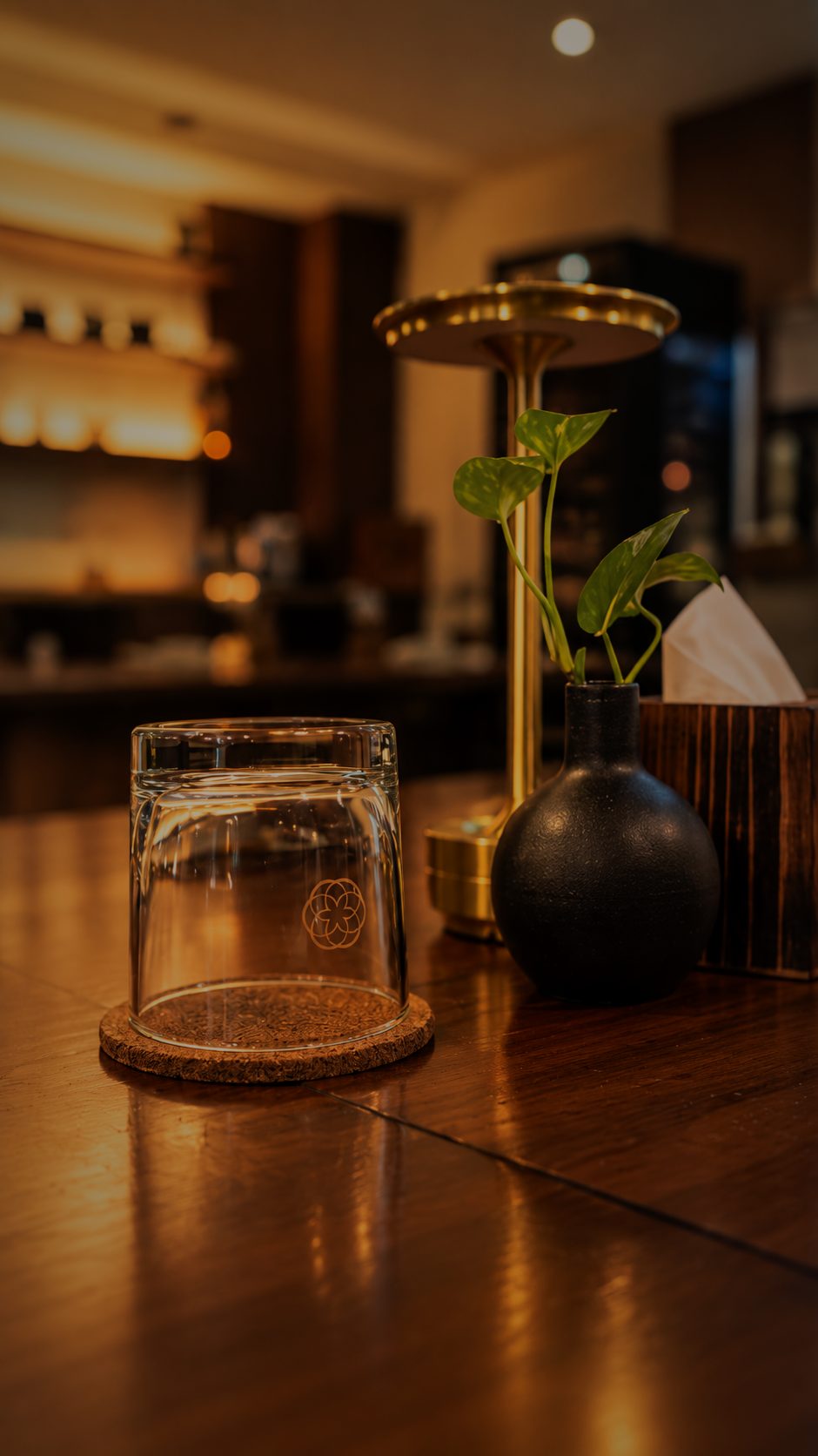 A gold table lamp glowing on the dark wood counter
