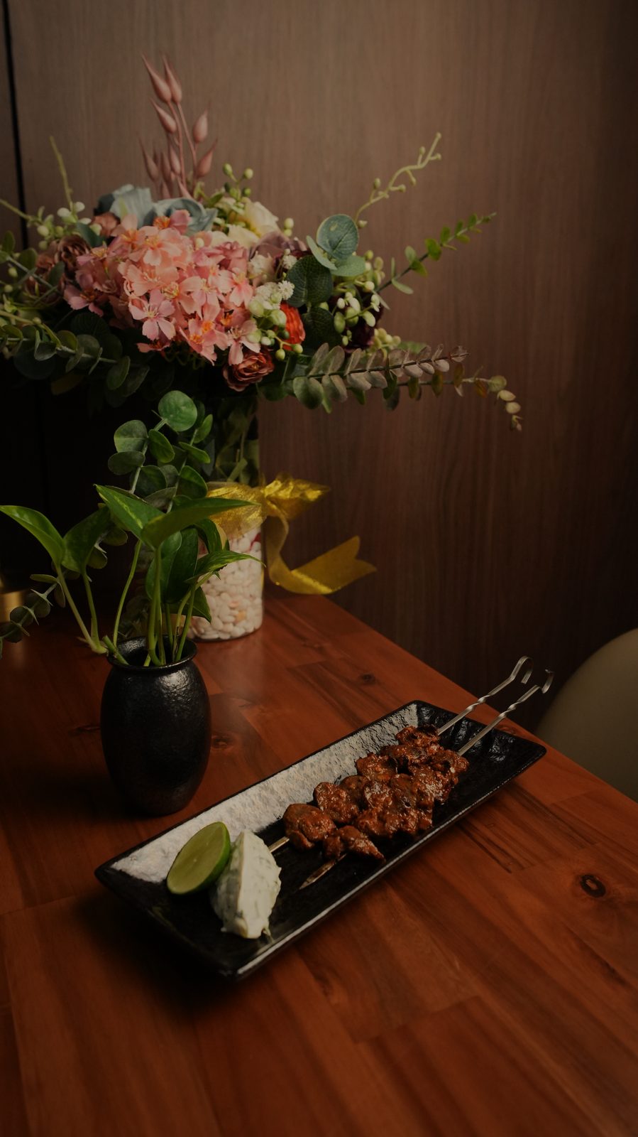 Grilled skewers on a black plate with lime