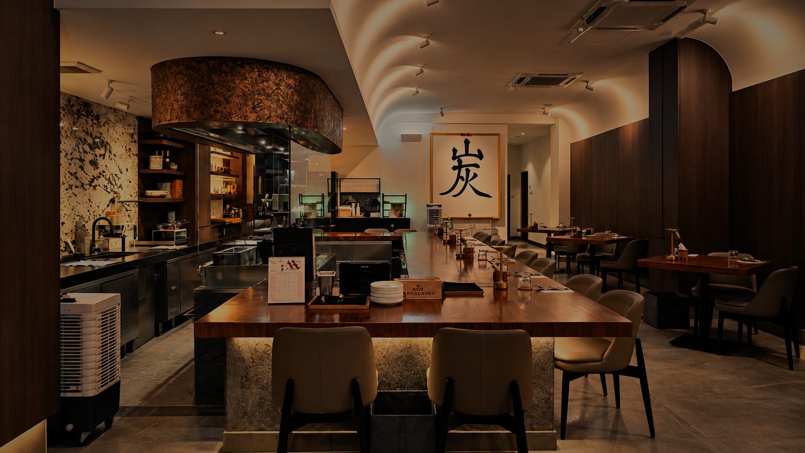 Counter seats facing the kitchen, with the 炭 calligraphy on the far wall