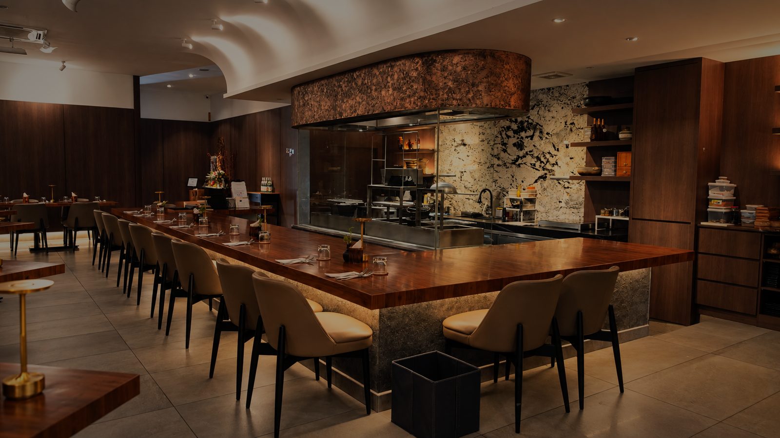 The main dining hall with its long counter and open kitchen, in low evening light