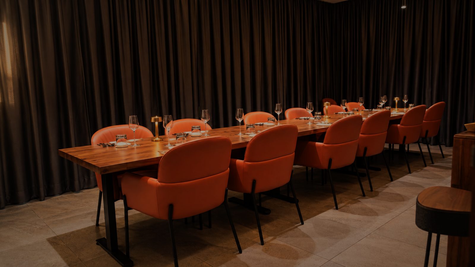 The private dining room's long timber table with orange chairs